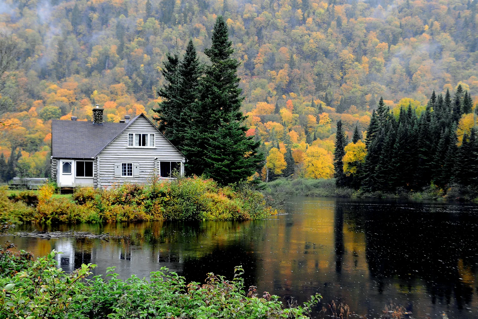 Chalet de bois en automne sur la rivière Jacques-Cartier, hébergement SEPAQ